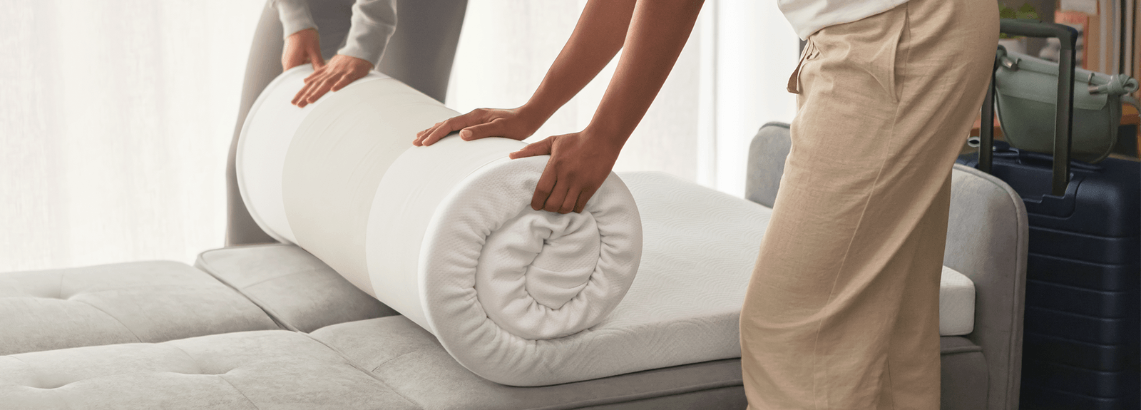 people unrolling 3 inch cloud topper on a futon